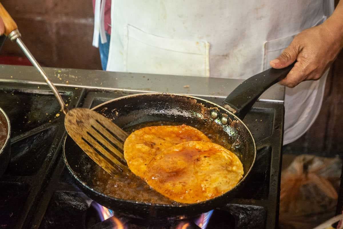 The tortillas for the enchiladas start out by being briefly fried in oil and chile sauce.