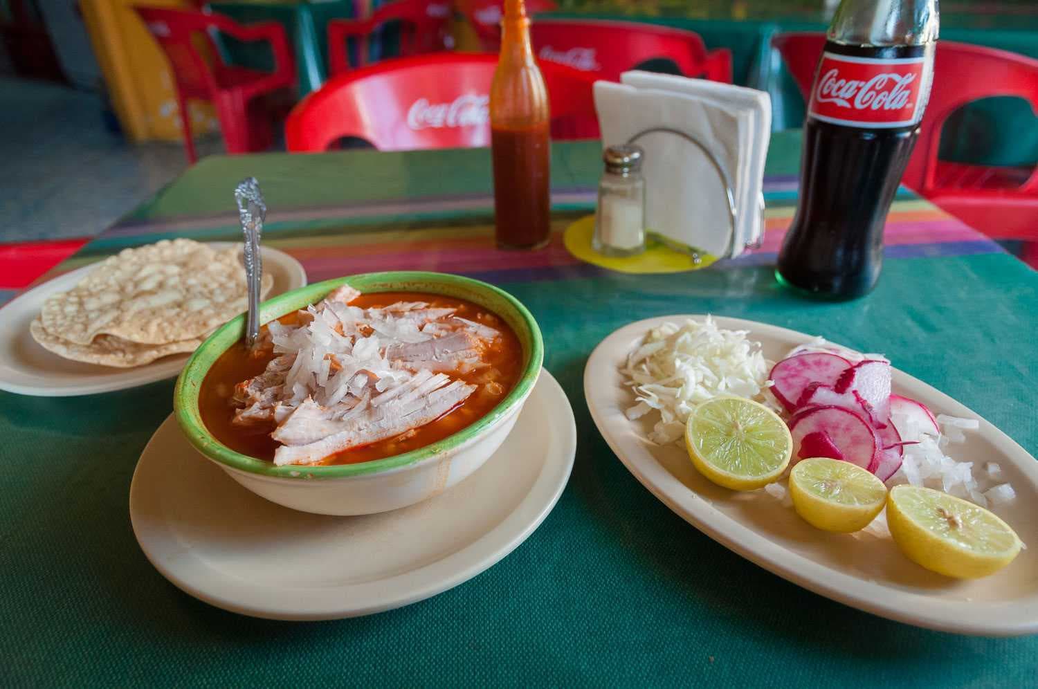 It's served with limes, chopped onion, radish slices, cabbage, and tostadas. Dip the tostadas in the broth or pile the pozole onto them.