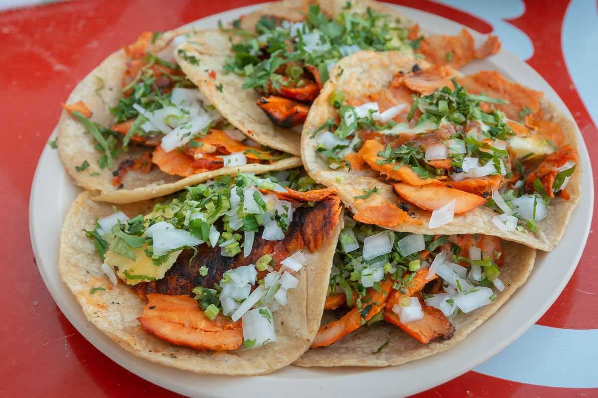 La dulzura del pequeño bocado de piña contrarresta el sabor de la carne marinada. Consigue el plato de cinco tacos de pastor por $50.