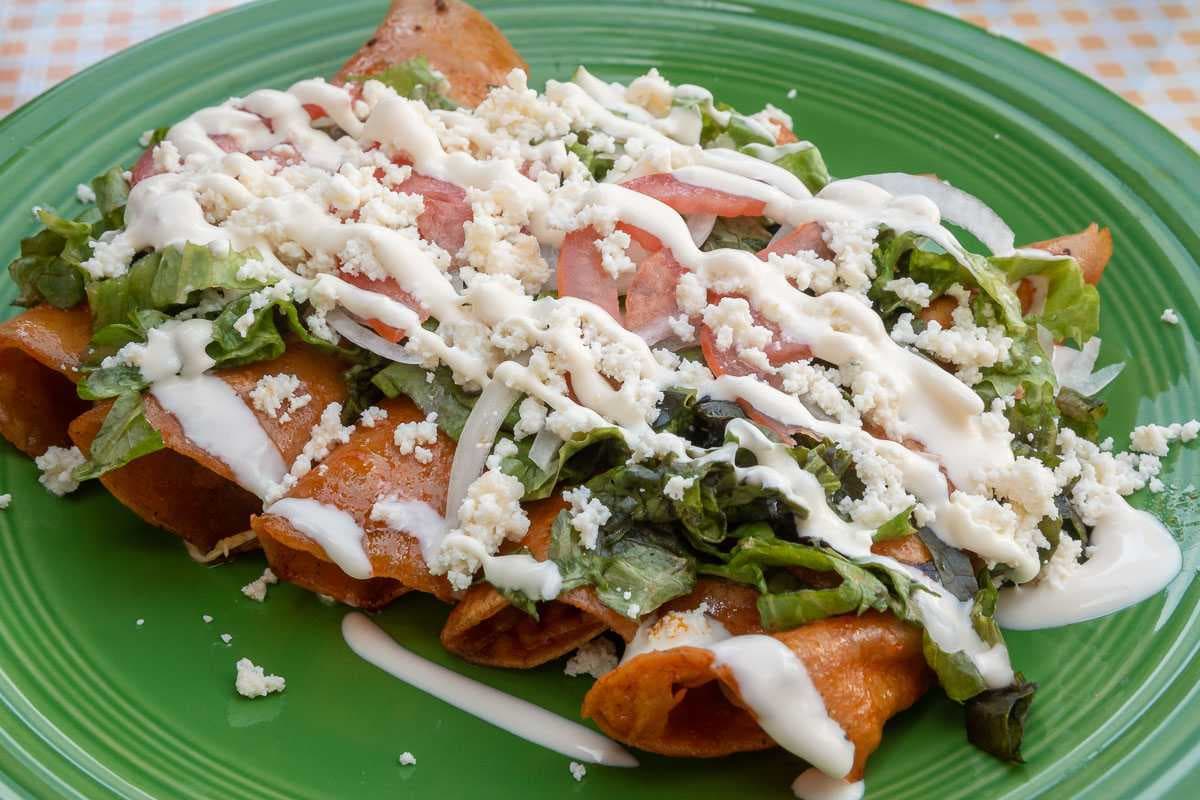 Enchiladas with red sauce. The tortillas for these enchiladas are first briefly fried in the chile sauce before being filled with chicken or cheese. Found at Lonchería Mary.