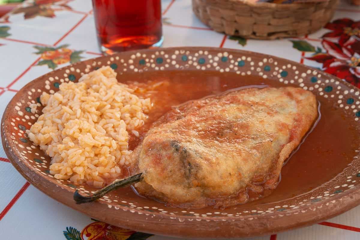 A prepared chile relleno in a bath of a non-spicy, tomato-based sauce.