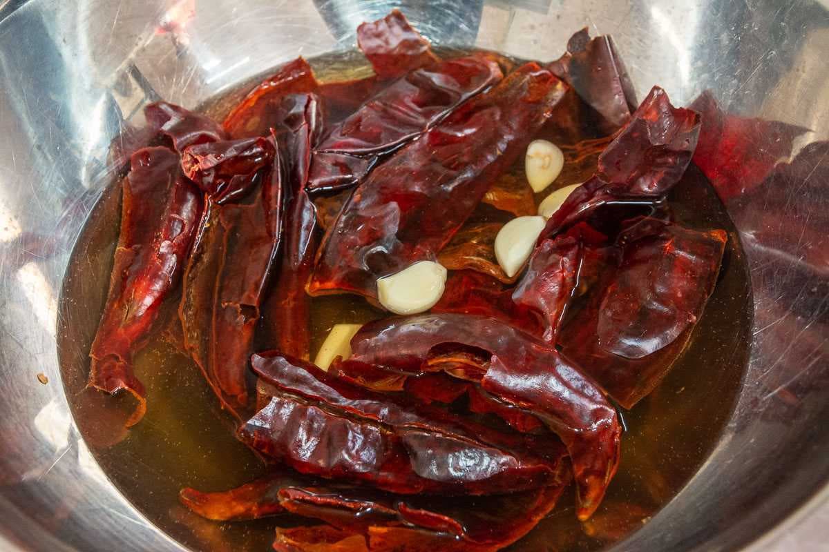 Guajillo chiles are commonly used to make red pozole. They hydrate by sitting in hot water for about ten minutes before being liquified in a blender.
